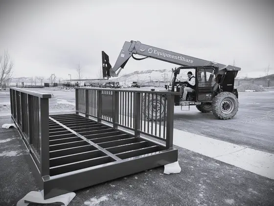 Wetzel Welding crew moving a custom steel guardrail panel with a telehandler outside the shop