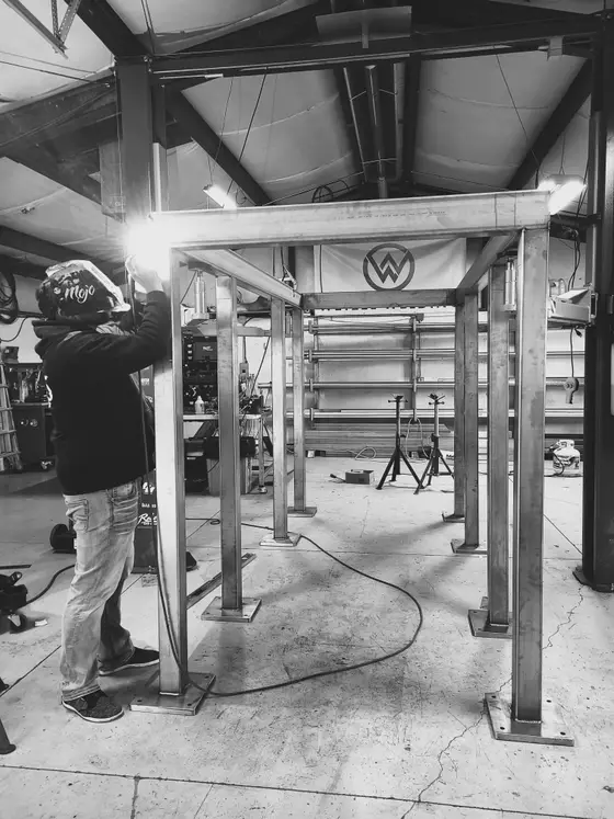 Wetzel Welding welder fabricating a large X-braced stainless steel support frame in the shop