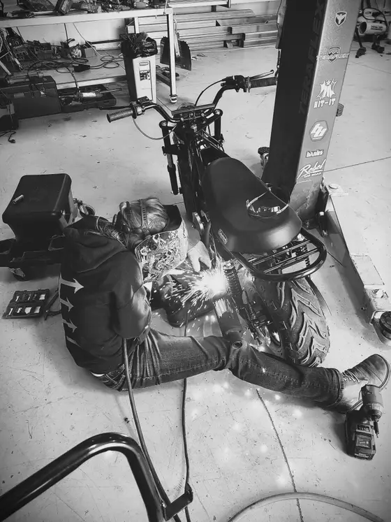 Wetzel Welding welder fabricating a custom bracket beneath a motorcycle on a lift