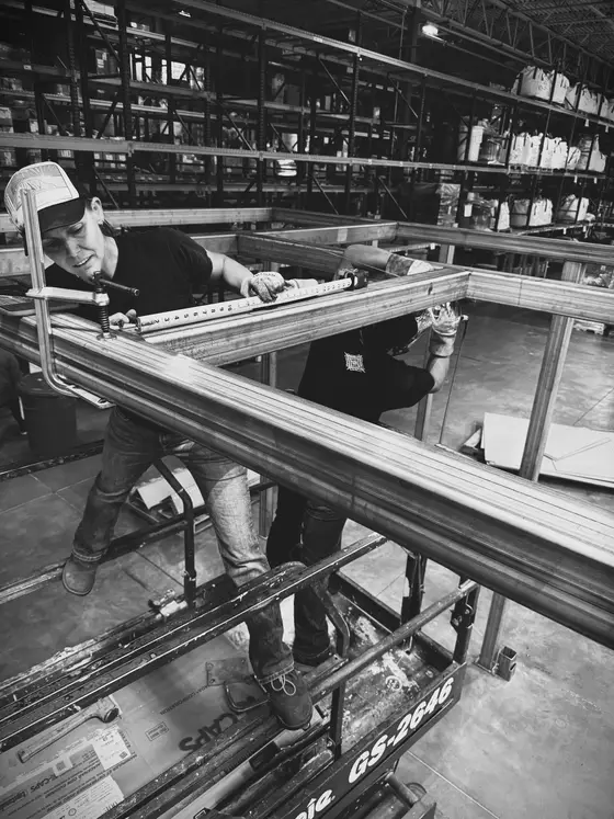 Wetzel Welding welders assembling a large stainless steel frame from a scissor lift
